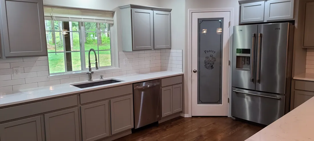 Refinished gray kitchen cabinets with subway tile and new hardware